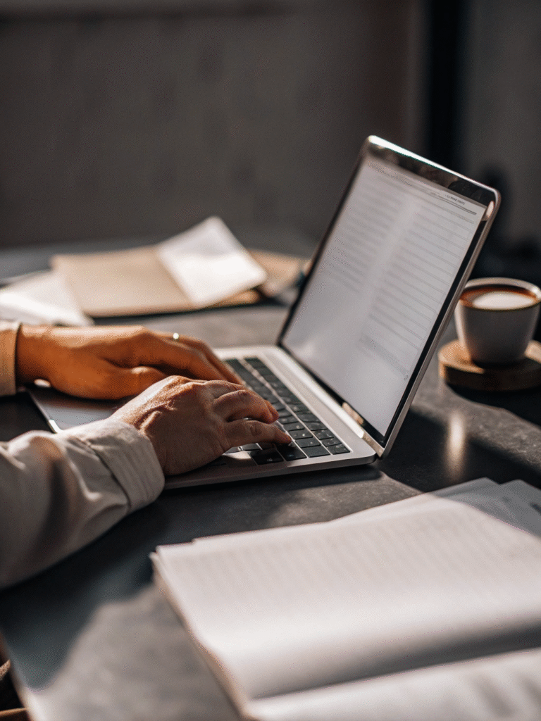 An office employee sits at his desk and enthusiastically types an article on a laptop.